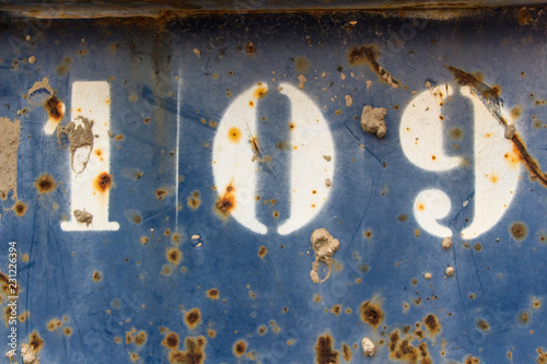 number hundred nine painted on rusty blue metal, number 109