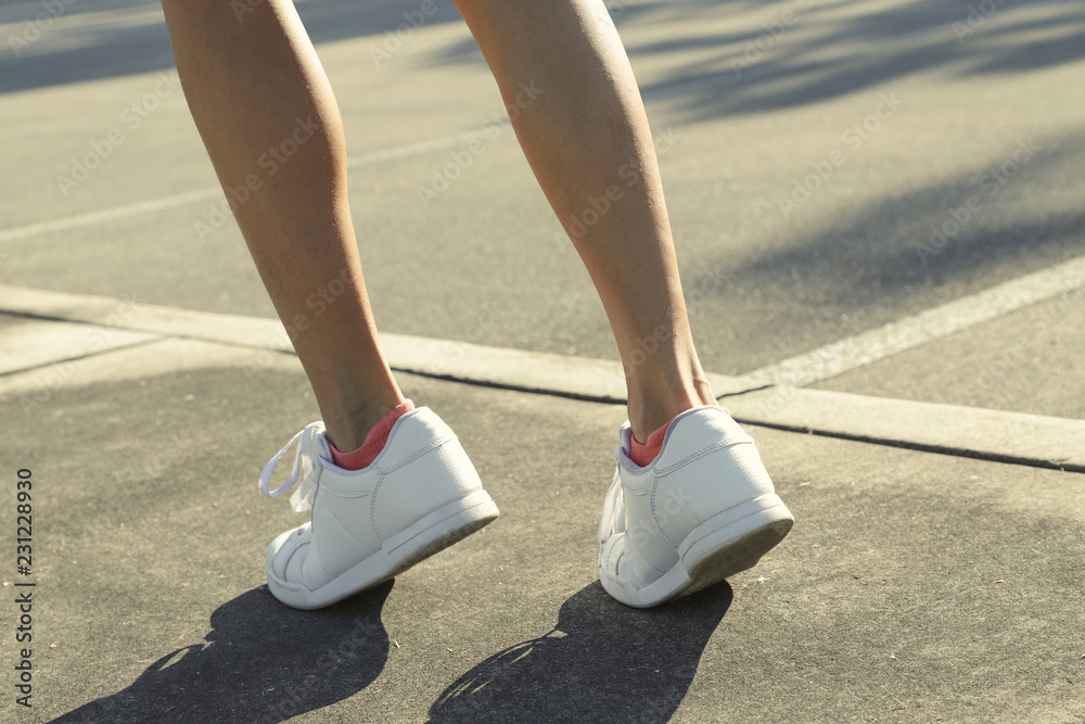 female legs in sneakers close up running down the road in the morning