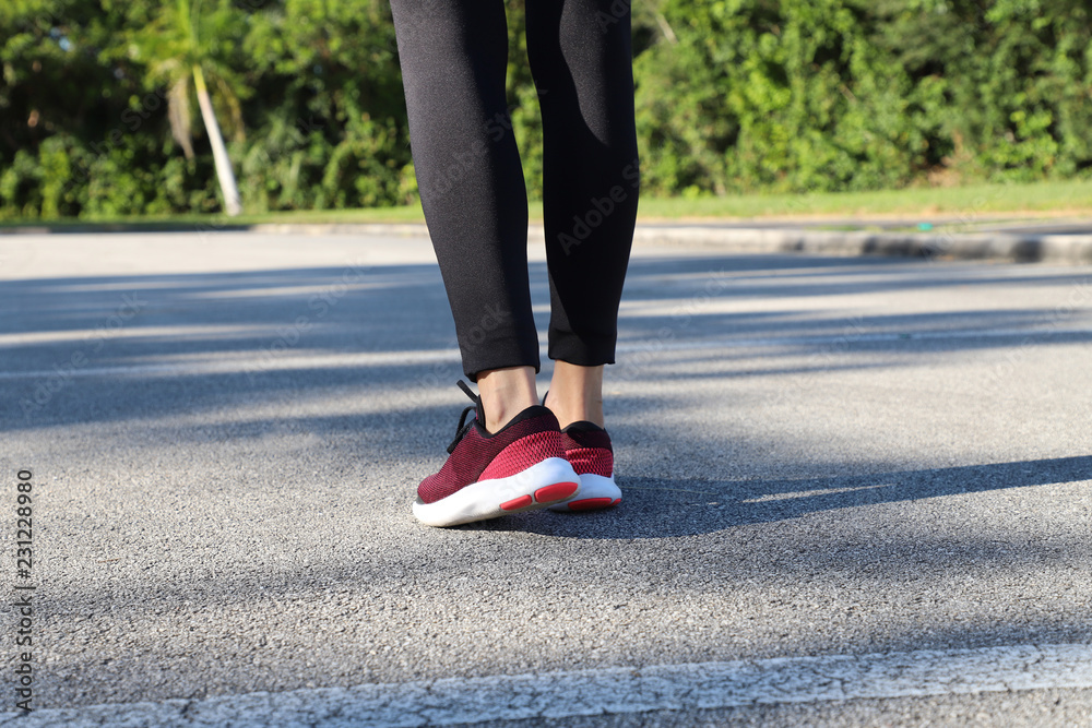 Runner woman feet running on road in the morning.