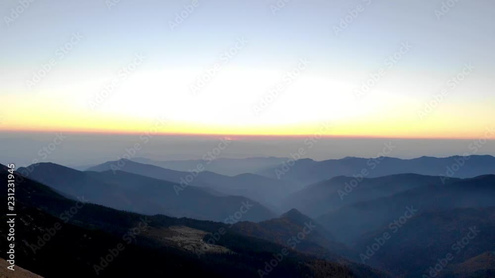 Drone aerial flying backwards over mountain ridge with man hiker standing walking on top looking into picturesque valley of endless silhouettes at sunset Drone aerial flying backwards over mountain ridge with man hiker standing walking on top looking into picturesque valley of endless silhouettes at sunset
