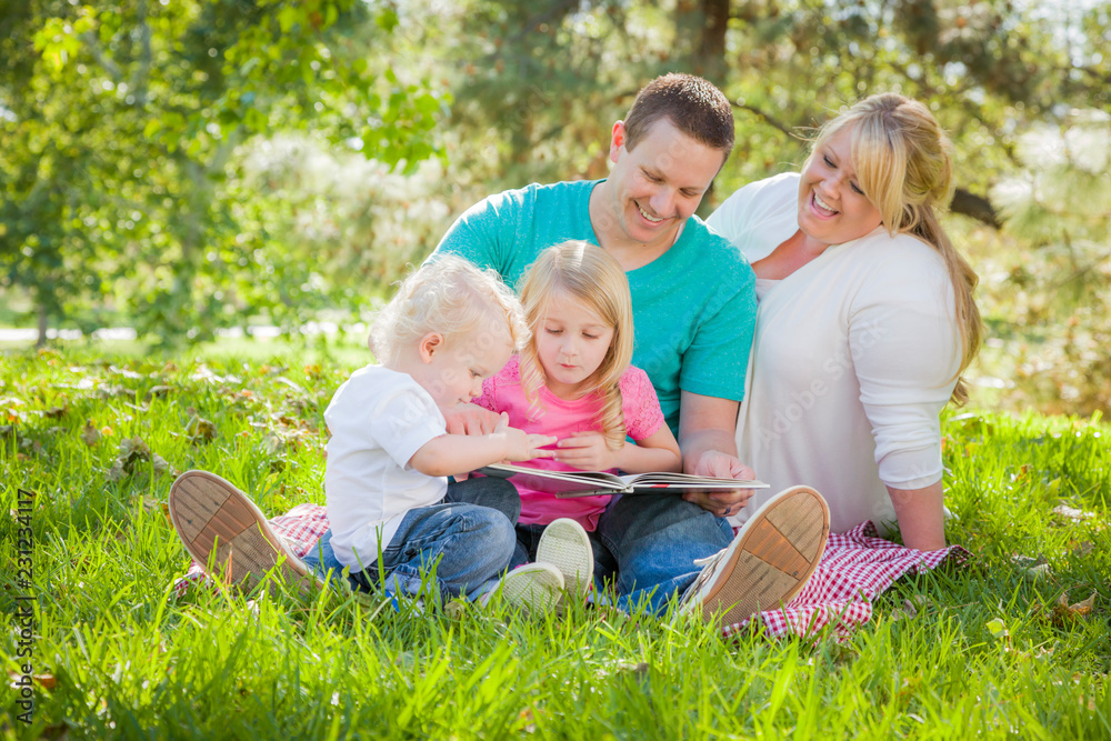 Fototapeta premium Young Family Enjoys Reading a Book in the Park