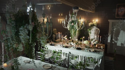 a table set with black arrows with food, wine glasses, flower vases, candlesticks with candles behind which stands two thrones