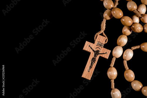 A brown rosary lying on a black background