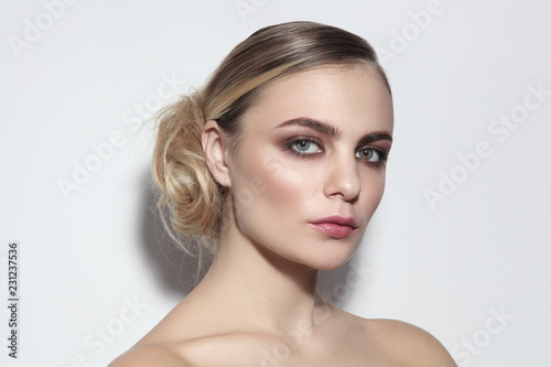 Young beautiful woman with light smoky eye make-up and fancy messy hair bun