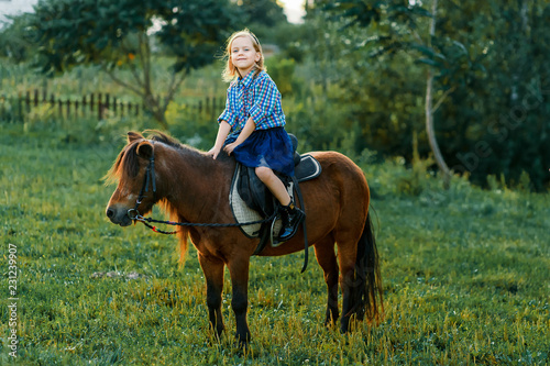 A girl and a pony outside at sunset. Nature near the water © Gorodetskaya