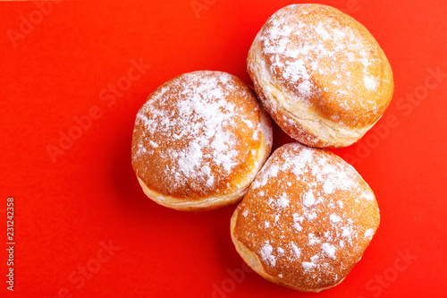 Tasty sweet donuts with powdered sugar on bright red background