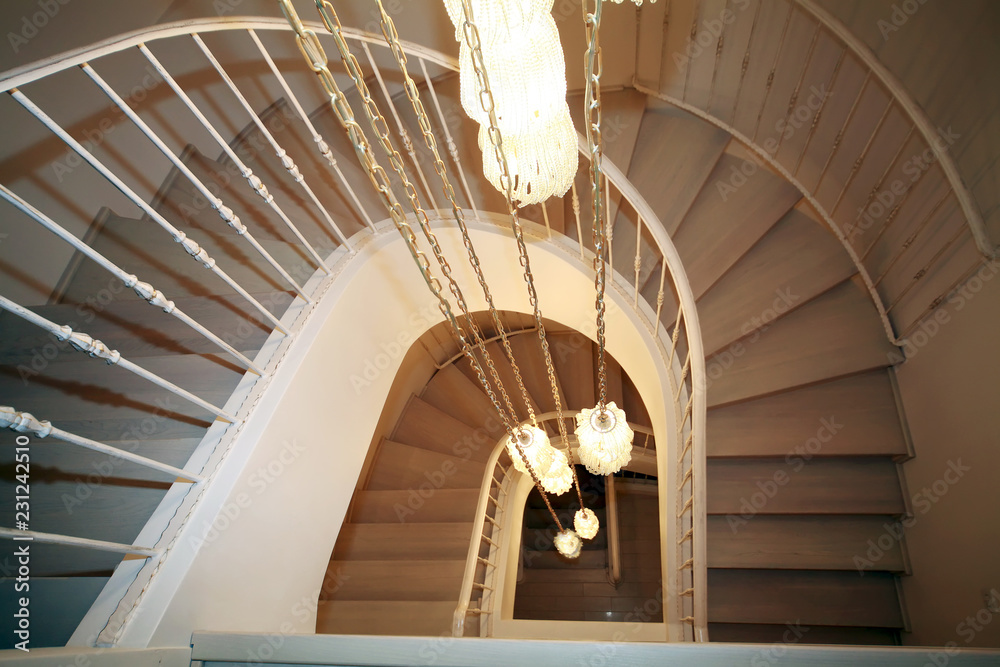 Obraz premium wonderful and very cozy spacious house of several floors with a beautiful wooden staircase and carved railing, with a fireplace and a white chandelier