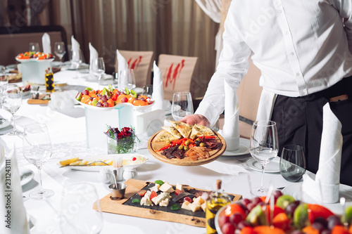 Waiter serving table in the restaurant preparing to receive guests.