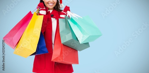 Composite image of beautiful brunette with santa hat holding