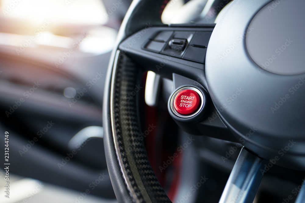 Obraz premium Sports car steering wheel with start - stop red button for engine start. Luxury modern car interior.