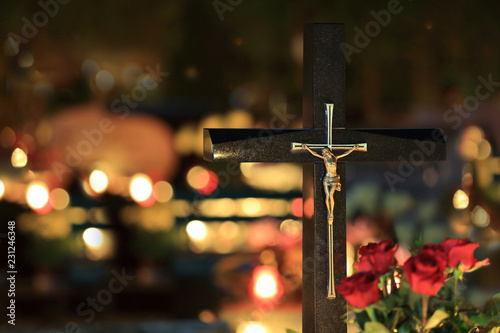 Piękny złoty wizerunek chrystusa na krzyżu na cmentarzu nocą w świetle palących się zniczy. photo
