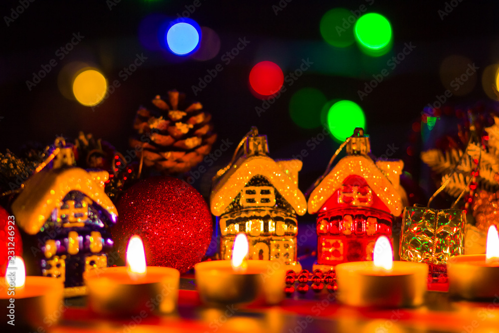 Merry Cristmas. Toy houses and candlelight. Christmas decorations on blurred background. Festive evening. Spruce branches and Christmas toys with bokeh. Copy space Merry Cristmas. Toy houses and candlelight. Christmas decorations on blurred background. Festive evening. Spruce branches and Christmas toys with bokeh. Copy space