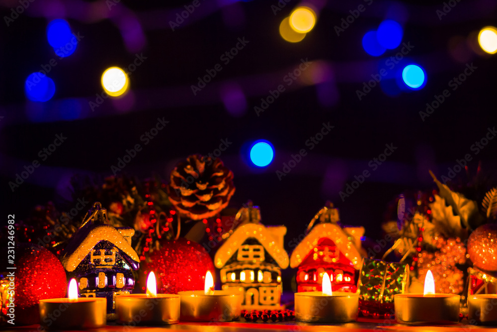 Merry Cristmas. Toy houses and candlelight. Christmas decorations on blurred background. Festive evening. Spruce branches and Christmas toys with bokeh. Copy space Merry Cristmas. Toy houses and candlelight. Christmas decorations on blurred background. Festive evening. Spruce branches and Christmas toys with bokeh. Copy space