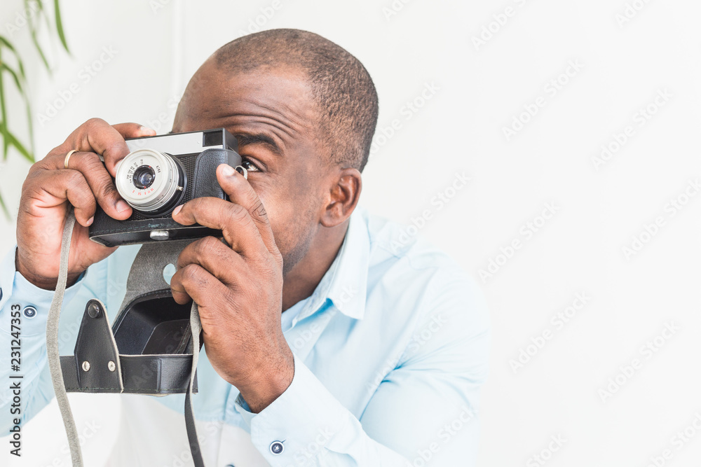 Portrait of a young afro american man taking pictures on an old vintage camera Portrait of a young afro american man taking pictures on an old vintage camera