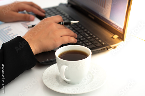 Businesswoman having coffee while using laptop at desk