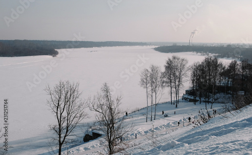 Winter city landscape with Smoking factory chimneys and winter park with walking people. © familylifestyle