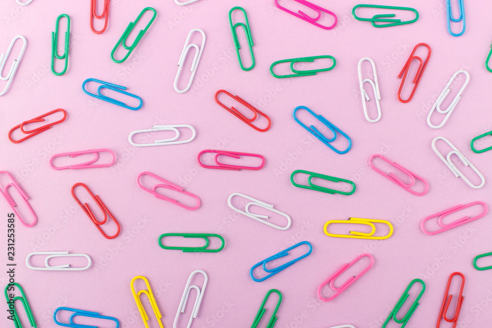 Background made from colored paper clips on the light pink base Background made from colored paper clips on the light pink base