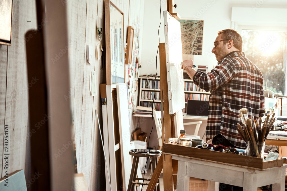 A painter in his studio working on a canvas at sunrise