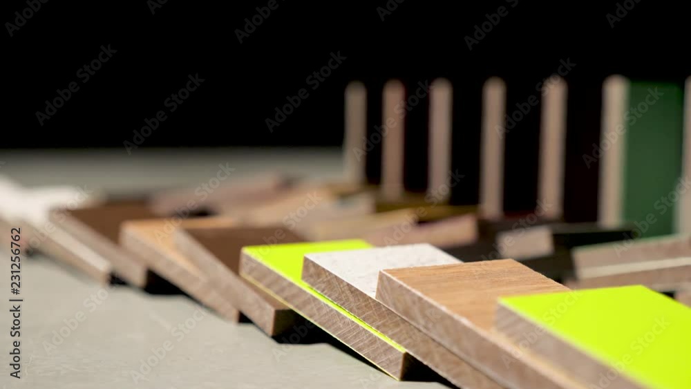 Domino effect concept with wooden blocks falling on each other. Colorful wood pieces dominoes falling down one by one. Side view.
