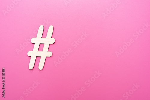 Hashtag sign made of wooden material on pink background