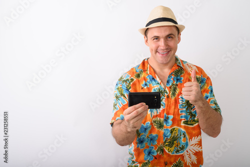 Studio shot of young happy muscular tourist man smiling while ta photo