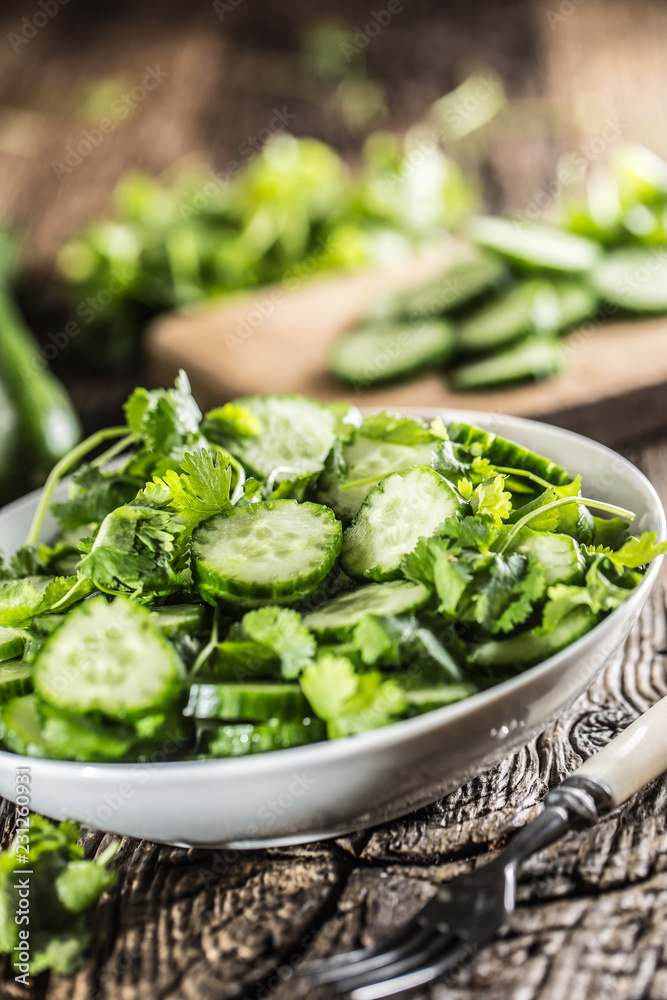 Sliced cucumber on a plate with parsley herb on rustic oak wood. Sliced cucumber on a plate with parsley herb on rustic oak wood.