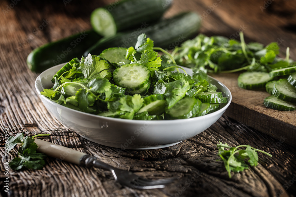 Sliced cucumber on a plate with parsley herb on rustic oak wood. Sliced cucumber on a plate with parsley herb on rustic oak wood.