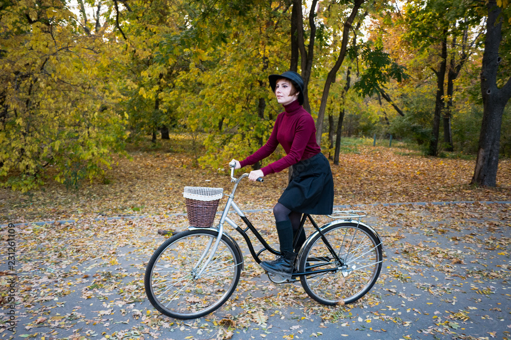 young woman riding on retro bicycle in the autumn park	