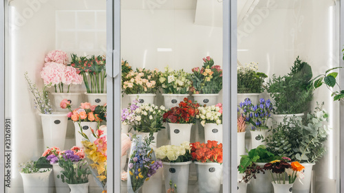 Fototapeta Naklejka Na Ścianę i Meble -  Flower shop concept. Different varieties fresh spring flowers in refrigerator room for flowers. Bouquets on shelf, florist business.