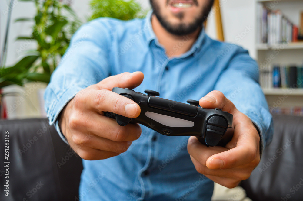 Determined young handsome man holding controller and trying hard to win on video games Determined young handsome man holding controller and trying hard to win on video games
