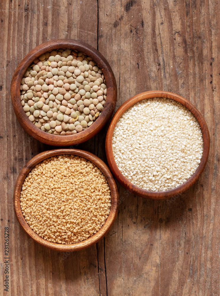 Organic lentils, couscous and sesame seeds in wooden bowls. Organic lentils, couscous and sesame seeds in wooden bowls.