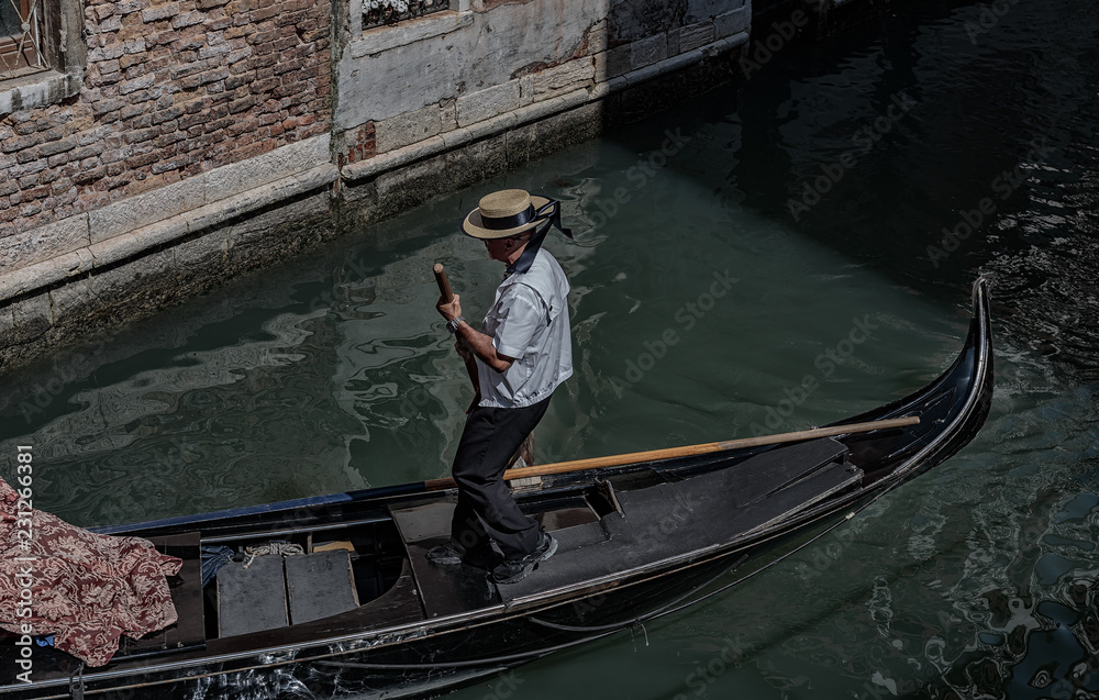 Gondolier rides gondola on the canals of Venice
