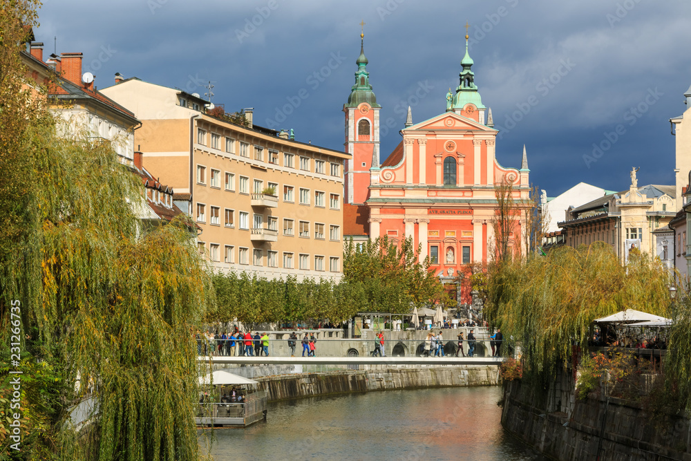 View of Ljubljanica river in old city with dark stormy clouds in the background on an autumn day, Ljubljana, Slovenia