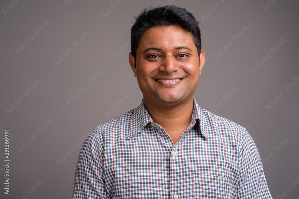 Portrait of young Indian businessman against gray background Portrait of young Indian businessman against gray background