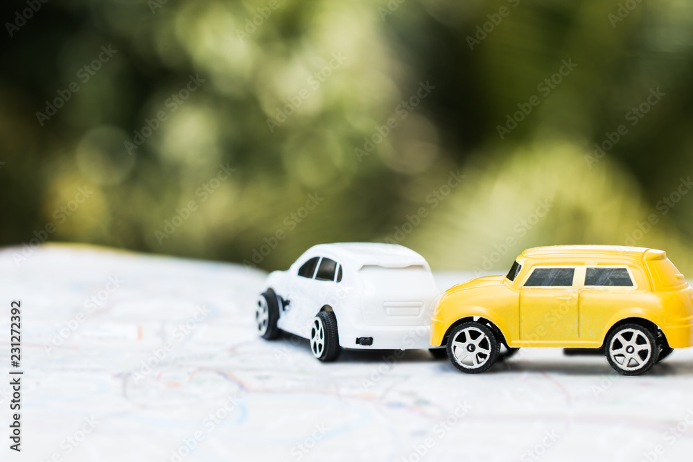 Car accident and Vehicle insurance concept : Two Miniature cars Collision crash on road, broken toys auto car on city map, green background.