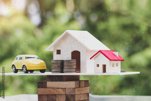 Photography Business real estate investment concept : Wooden home, car with stack of money coins on wooden blocks scales in balance
