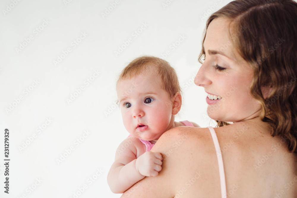 happy beautiful young mamma holding her 4 months old baby girl, back view