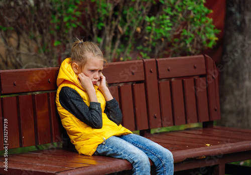 Teenager girl sitting alone on a bench and crying