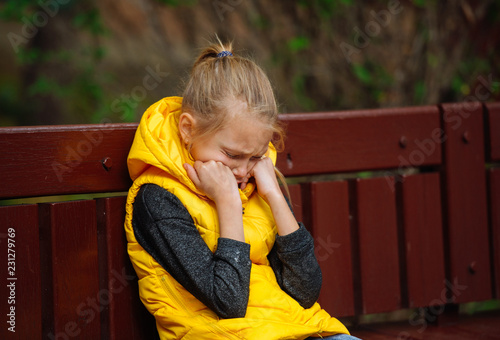 Teenager girl sitting alone on a bench and crying