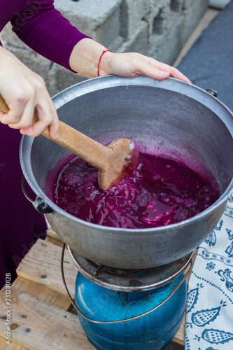 Cooking grape juice, corn and white flour in big pot boiler mixing with wooden spoon for pelamushi, tatara or churchkhela - traditional Georgian dessert sweets with walnuts or hazelnuts. photo