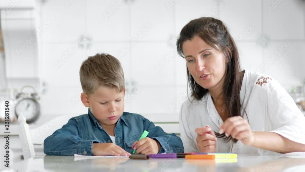 Portrait confident boy drawing picture on paper using colored felt-tip pen mother admiring son Portrait confident boy drawing picture on paper using colored felt-tip pen mother admiring son