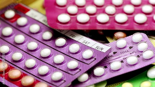 Oral contraceptive pill on pharmacy counter with colorful pills strips background.