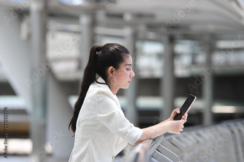 Pretty young Asian woman using mobile smart phone on street of city background. Social network concept