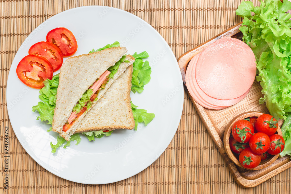 Top view of sanwiches with ham and tomatoes vegetable on dish,and wooden board Top view of sanwiches with ham and tomatoes vegetable on dish,and wooden board