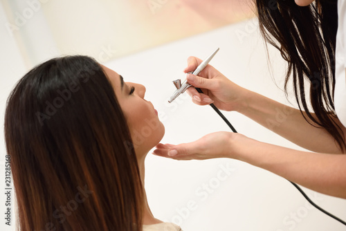 Make-up artist using aerograph making an airbrush make up photo