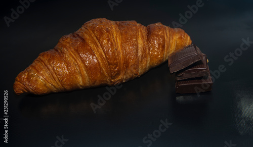 cloup line of fresh baked croissant with chocolate bars black background