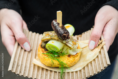 Close up photo of gourmet arepa  traditional Colombian corn patties  with blood sausage  head cheese  zucchini  and sauce at a street food market fair festival