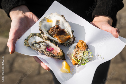 Close up of raw, fried, and smoked gourmet oysters at a street food market fair festival