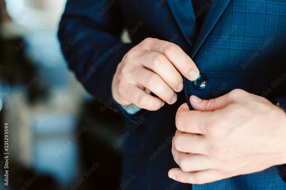 Man in a jacket, a man fastens a button on his jacket, groom in a tie