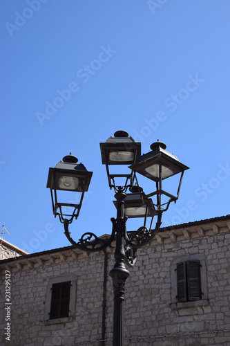 mediterranean scene with retro street lantern and rustic house facade, decorative and nostalgic street lamp in front of azure sky